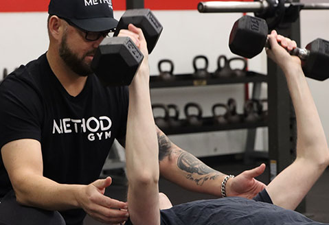 A Method Gym personal trainer provides guidance to a gym member