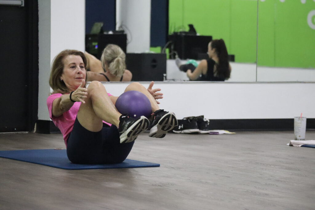 A woman performing a deep core exercise in at group fitness class at Method Gym.
